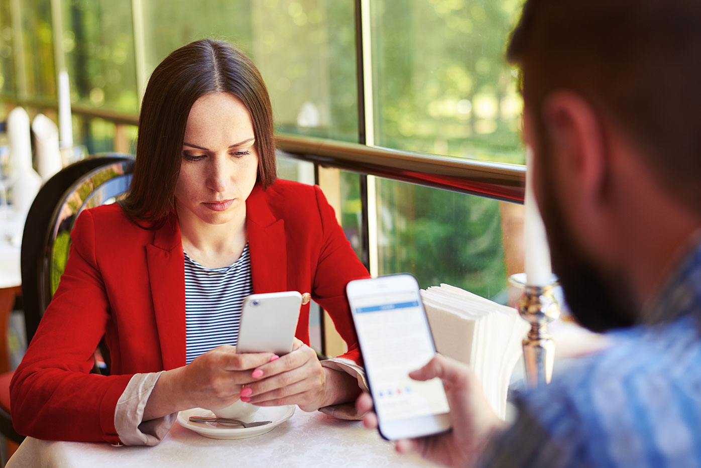 A man and woman sitting at a table on their smartphones