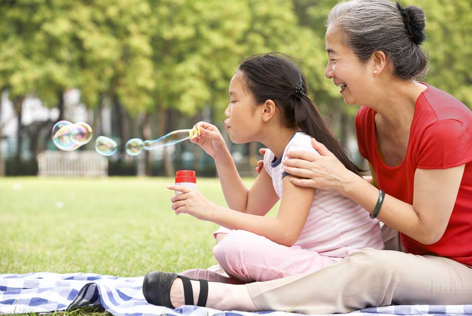 A grandmother and grandchild picnic and blow bubbles